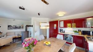 a kitchen with red cabinets and a table with flowers on it at 54° Nord Wohnung 1 in Grömitz