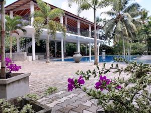 a resort with a pool and palm trees and purple flowers at Seetharama Garden of Life in Beruwala