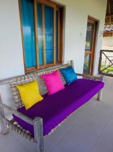 ławka z kolorowymi poduszkami siedzącymi przed oknem w obiekcie SECRET PLACE HOTEL by HELLO TANZANIA TOURS& SAFARIS w mieście Makunduchi