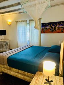 1 dormitorio con 1 cama y 1 mesa con lámpara en WHITE Nyumba en Malindi