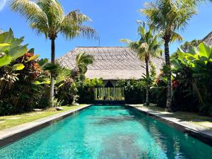 a swimming pool in front of a house with palm trees at Karmagali Suites Adults only & Private Pool Family Villas in Sanur