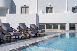 - une piscine avec des chaises longues à côté d'un bâtiment dans l'établissement Santorini Palace, à Fira