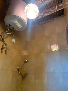 a bathroom with a shower with a light on the ceiling at بيت النحوي التراثي _ Bait Al Nahwai in Al Ḩamrāʼ