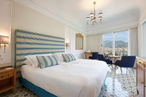 sypialnia z dużym białym łóżkiem i żyrandolem w obiekcie Grand Hotel Capodimonte w Sorrento