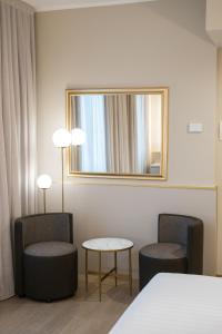 um quarto de hotel com duas cadeiras e um espelho em Hotel Nasco em Milão