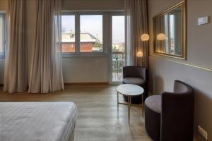 a hotel room with a bed and two chairs and a window at Hotel Nasco in Milan