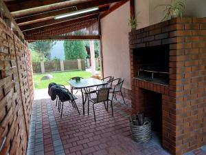a patio with a table and chairs and a brick fireplace at Domek Chmiel I nad Jeziorem Tarnobrzeskim in Chmielów