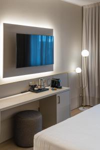 a room with a desk with a television on a wall at Hotel Nasco in Milan
