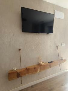 TV de pantalla plana en la pared con estantería de madera en Alojamiento Rural El Cerro, en Fresneda de la Sierra