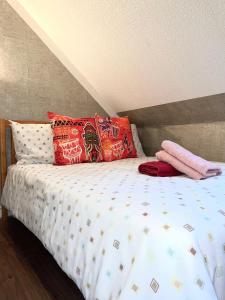 ein Bett mit bunten Kissen darüber in der Unterkunft Crescent Loft Apartment - 1 Bedroom in Goodmayes