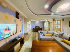 sala de estar con sofá y TV de pantalla plana en Pendeza La Casa, en Naivasha