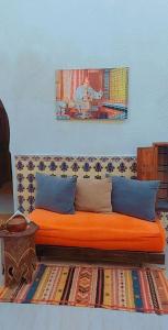 un sofá naranja con almohadas azules y una pintura en la pared en Riad Diafa en Rabat