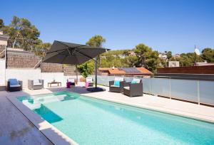 - une piscine avec des chaises et un parasol sur le toit dans l'établissement Villa Alzina en montemar, à Castelldefels
