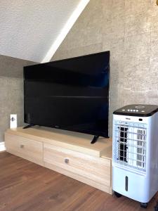 a large flat screen tv sitting on a wooden entertainment center at Crescent Loft Apartment - 1 Bedroom in Goodmayes