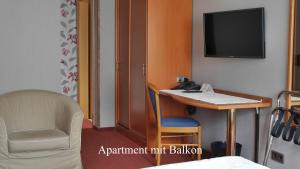 um quarto com uma secretária, uma televisão e uma cadeira em Hotel-garni-Kachelburg em Dieblich