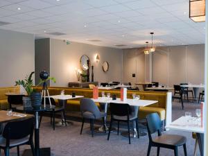 un comedor con mesas, sillas y mesa en Novotel Bayeux, en Bayeux