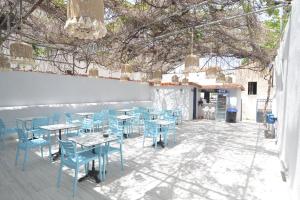 a patio with blue tables and chairs and a building at Ados Hotel in Cesme