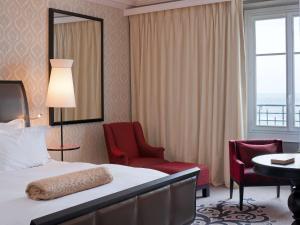a hotel room with a bed and a desk and a chair at Le Grand Hotel de Cabourg - MGallery Hotel Collection in Cabourg