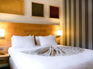 a bedroom with a large white bed with two lamps at Mercure Saint-Lary in Saint-Lary-Soulan