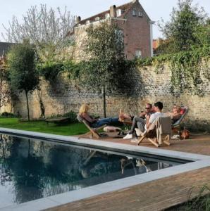 a group of people sitting in chairs by a swimming pool at B'Guest Sleep & Retreat in Bruges