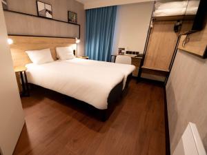 una habitación de hotel con una gran cama blanca. en ibis Creil Sur Oise, en Villers-Saint-Paul