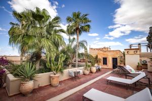 a patio with chairs and palm trees on a building at La Villa Nomade in Marrakesh