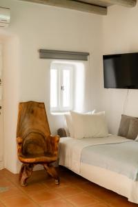 een slaapkamer met een bed en een stoel en een tv bij Honey Bee House in Mykonos-stad