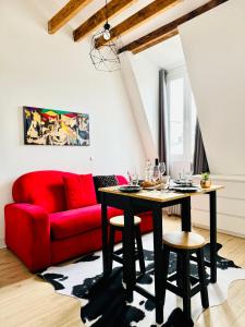 uma sala de estar com um sofá vermelho e uma mesa em Apartment Direct Views of Eiffel Tower & Sacré-Coeur from Mezzanine - 10 mins to Paris Center em Paris