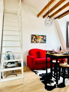 uma sala de estar com um sofá vermelho e uma mesa em Apartment Direct Views of Eiffel Tower & Sacré-Coeur from Mezzanine - 10 mins to Paris Center em Paris