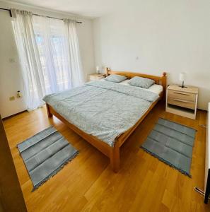 a bedroom with a large bed with two rugs at Apartman Latice in Tomislavgrad