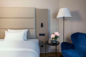 a bedroom with a bed and a chair and a lamp at NH Berlin Kurfürstendamm in Berlin