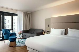 ベルリンにあるNH ベルリン クアフュルステンダムの大きなベッドとソファが備わるホテルルームです。