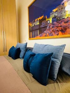 ein Bett mit blauen Kissen und ein Gemälde an der Wand in der Unterkunft Sicilia Vacation in San Vito lo Capo