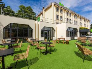 un groupe de tables et de chaises devant un bâtiment dans l'établissement Ibis Styles Bobigny Centre Préfecture, à Bobigny