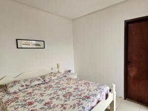 1 dormitorio con 1 cama con colcha de flores en Flor de Lótus Suites en Tamandaré