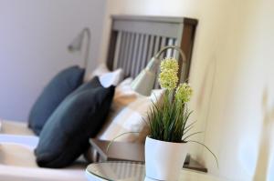 a potted plant on a table in front of a bed at Landhotel Rehedyk in Sankt Michaelisdonn
