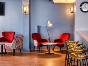 uma sala de espera com cadeiras vermelhas e uma mesa em The Harlow Hotel By AccorHotels em Harlow