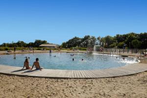 duas pessoas sentadas numa piscina na praia em Chalet site naturel proche lac, 20 mn des plages Vendee - 6 pers em La Chapelle-Hermier
