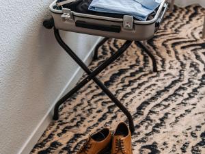 une paire de chaussures et une valise sur tapis dans l'établissement ibis Styles Ancenis Centre, à Ancenis