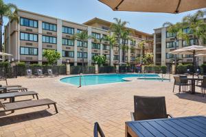 博伟公园Doubletree by Hilton Buena Park的建筑物前有带桌椅的游泳池