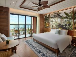 a bedroom with a large bed and a living room at Mövenpick Resort Phan Thiet in Phan Thiet
