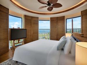 Mövenpick Resort Phan Thiet في فان ثيت: غرفة نوم بسرير ابيض وتلفزيون بشاشة مسطحة