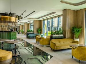 a lobby with yellow chairs and tables and windows at Novotel Tbilisi Center in Tbilisi City
