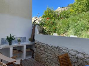 a patio with a stone wall and chairs and flowers at La casita Azul in Cazorla