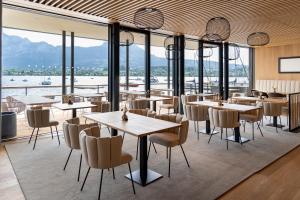 un restaurante con mesas, sillas y ventanas grandes en Apollo AchtQuartier Das Hotel am Mondsee, en Mondsee