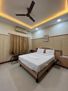 a bedroom with a large bed with a ceiling fan at Anand Regency Majestic in Bangalore
