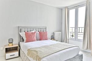 una camera bianca con un grande letto con cuscini rossi di Appartement paisible et moderne - Gagny a Gagny