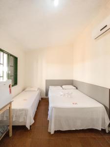 two beds in a room with white sheets at Plaza Hotel in Jataí