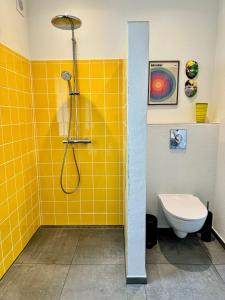 y baño de azulejos amarillos con ducha y aseo. en Ellens Have, lejlighed Beate, en Ebeltoft