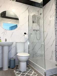 uma casa de banho com um WC, um chuveiro e um lavatório. em Crescent Apartment - Two bedroom em Goodmayes